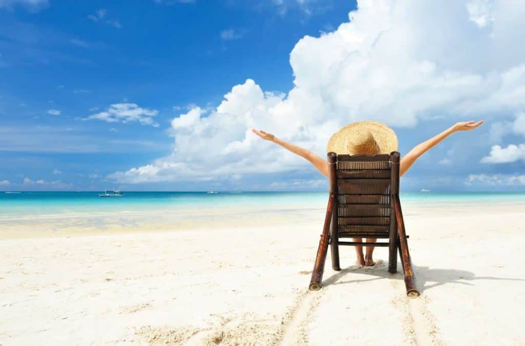 Ein mensch sitzt im Liegestuhl am Strand und freut sich