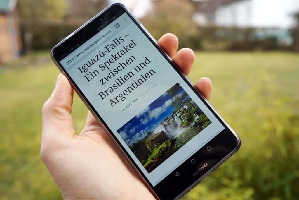 Eine Hand zeigt ein Smartphone darauf zu sehen eine Reiseblog