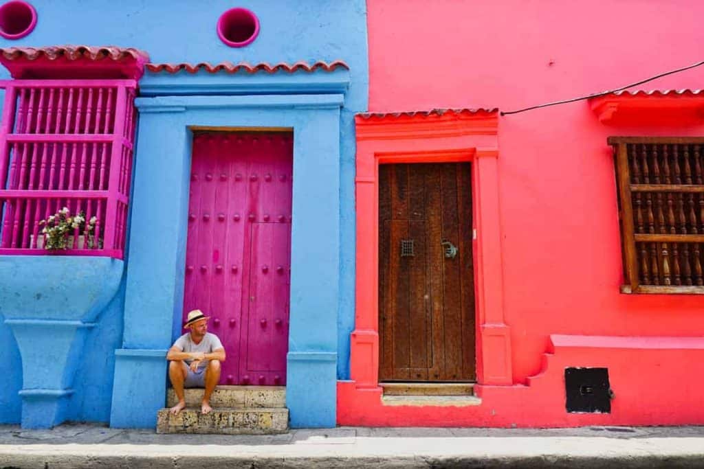 Mann sitzt vor einem bunten Haus in Cartagena