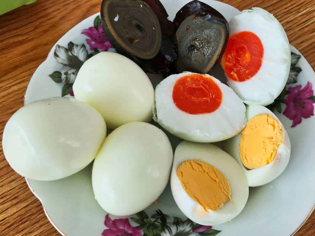 Normale Eier, ein rötlich verfärbtes Salzei und ein fermentiertes schwarzes hundertjähriges Ei auch Century Egg genannt
