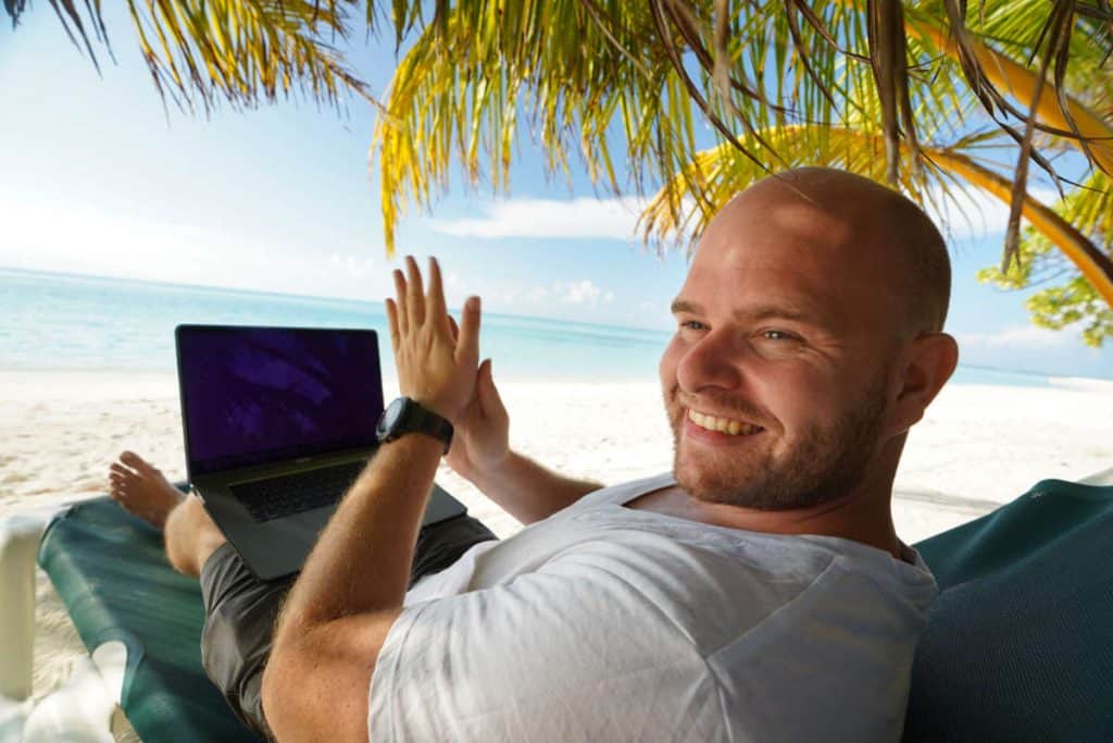 Mann mit Laptop am Strand